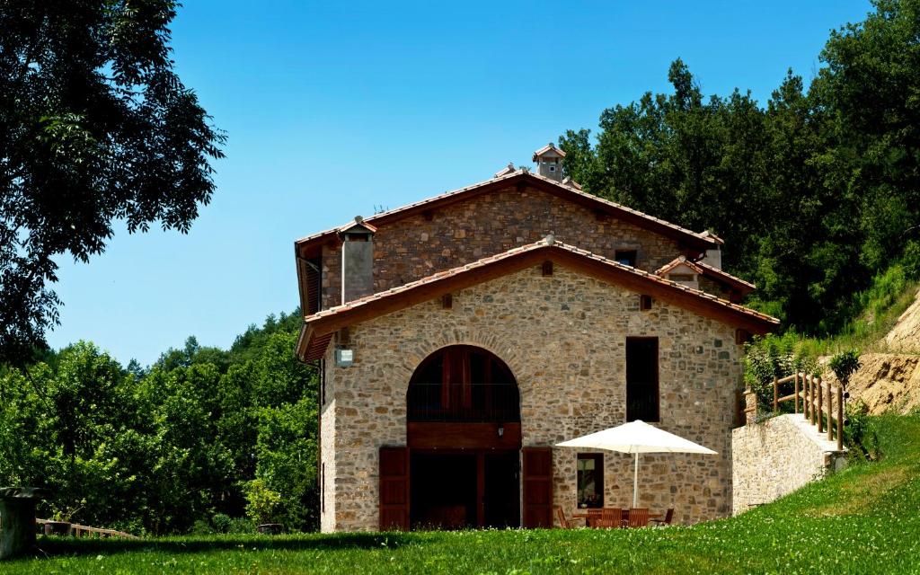 a small brick building with an umbrella in front of it at Mas Serrat de la Teia in Sant Joan de les Abadesses