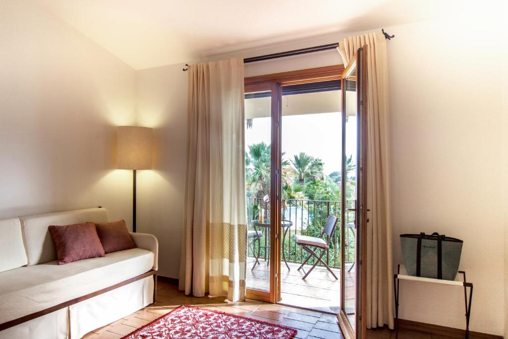 a living room with a couch and a sliding glass door at Hotel Aquadulci in Chia