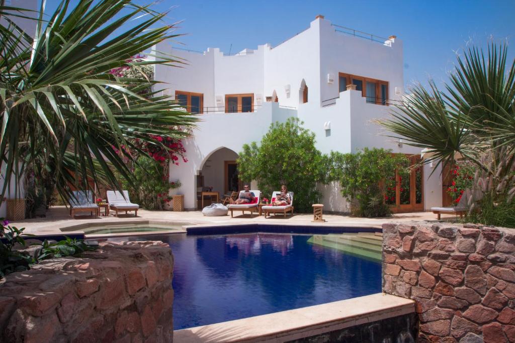 a villa with a swimming pool in front of a house at Red C Villas in Dahab
