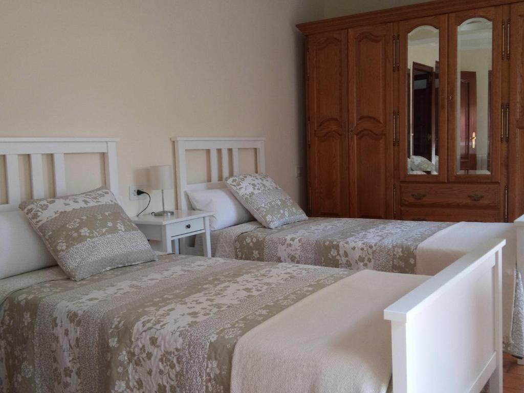 a bedroom with two beds and a cabinet at Casa Do Zoqueiro in Arzúa