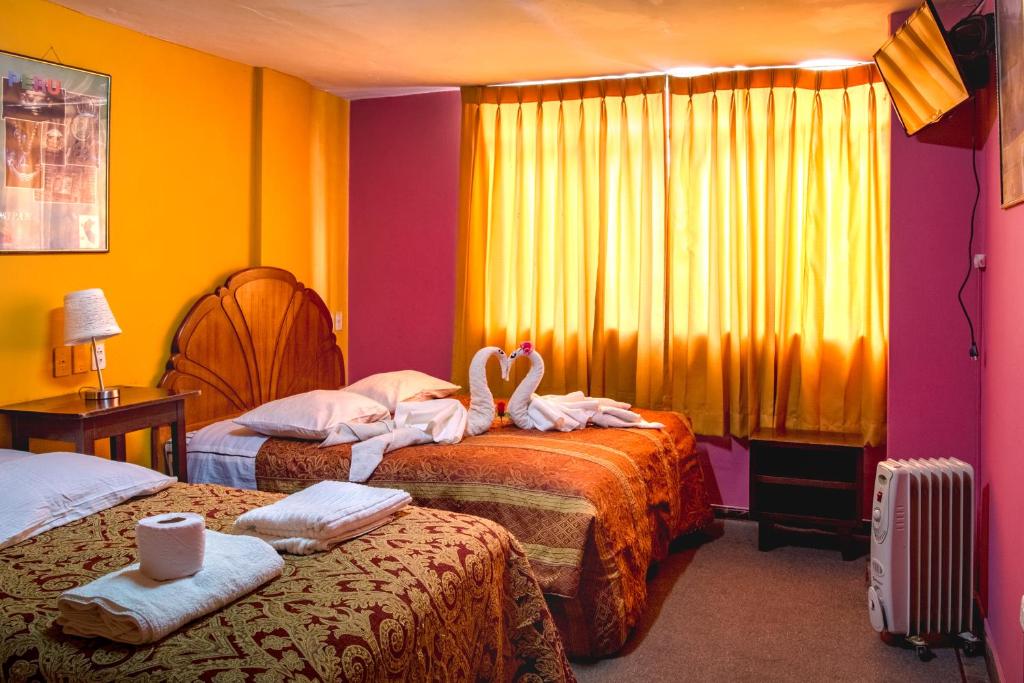 two beds in a room with two swans on them at Hostal Virgen de Las Nieves II in Puno