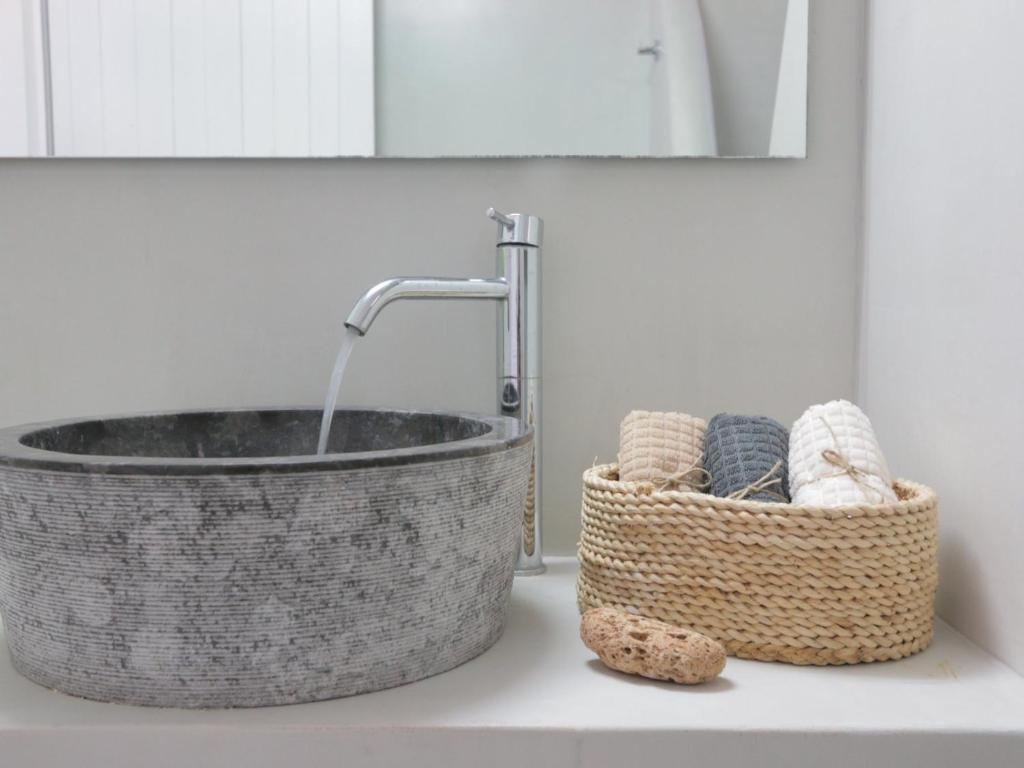 a bathroom sink with a basket and a tub at Bonatsa House in Agios Georgios