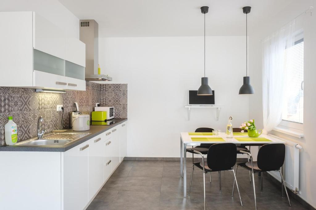 cocina con armarios blancos, mesa y sillas en Apartment Zelená zahrada en Mladá Vožice