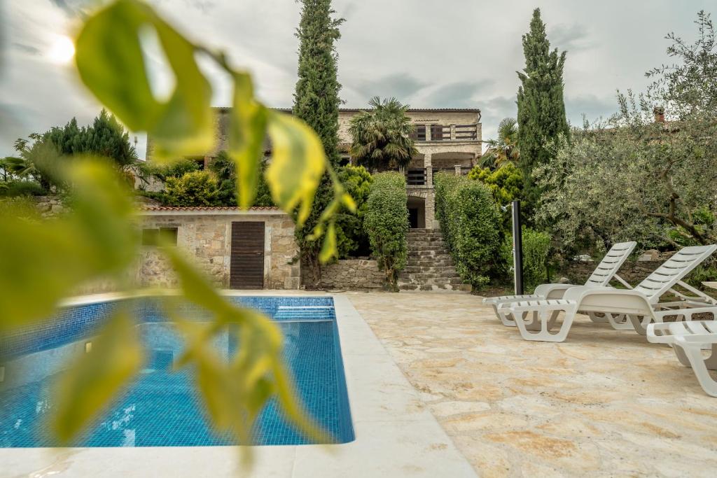 a house with a swimming pool and two lounge chairs at Holiday Home Vizinada in Vižinada