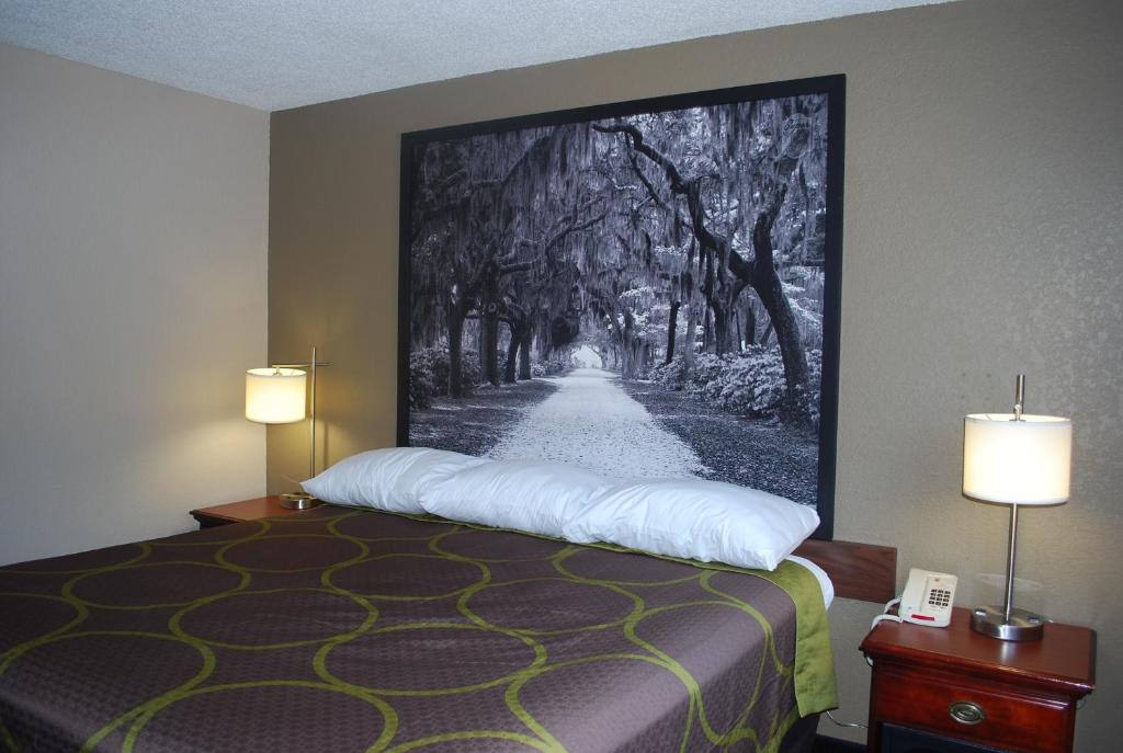 Zimmer mit einem Bett und einem Gemälde an der Wand in der Unterkunft Super 8 by Wyndham Warner Robins in Warner Robins