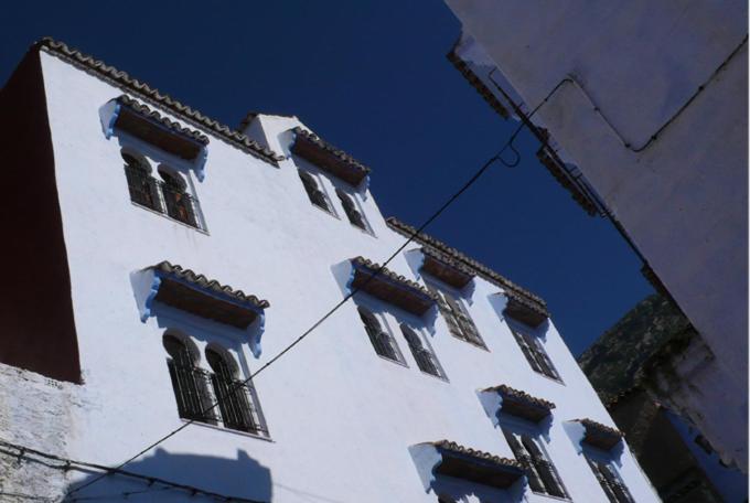 een hoog wit gebouw met ramen aan de zijkant bij Hôtel Ras El Maa in Chefchaouene