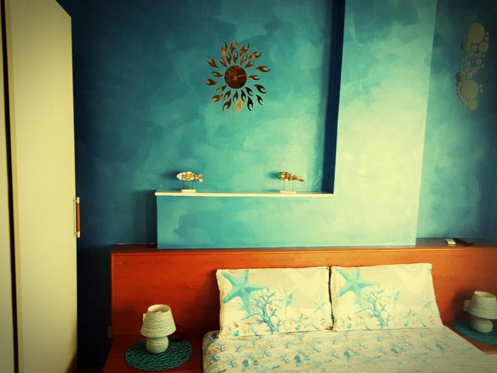 1 dormitorio con pared azul, cama y espejo en La Dea del mare, en Scilla