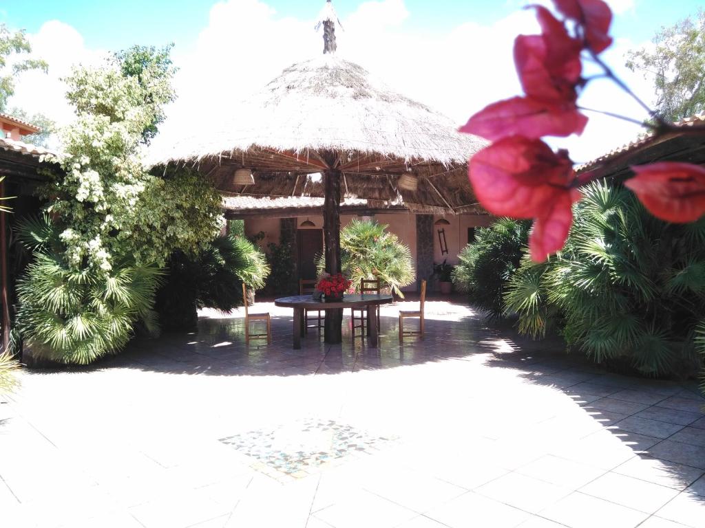ein Gebäude mit einem Tisch und einem Strohschirm in der Unterkunft Agriturismo la Mimosa in Putzu Idu