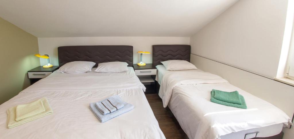 two beds in a room with white sheets and green pillows at Guesthouse Stari Grad in Mostar