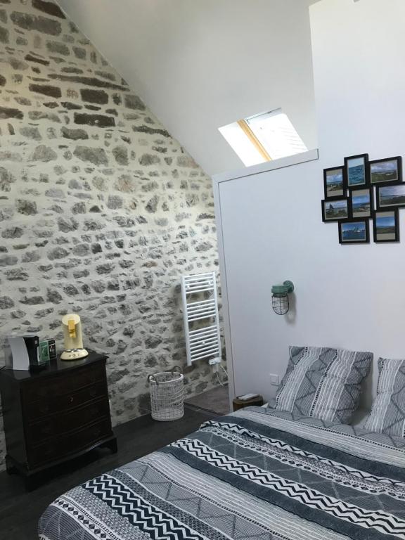 a bedroom with two beds and a stone wall at Chez Natacha et Adrien in Regnéville-sur-Mer