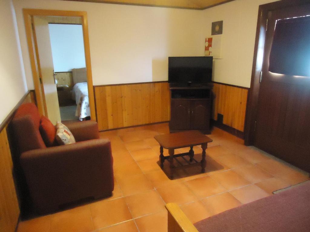 ein Wohnzimmer mit einem TV, einem Stuhl und einem Tisch in der Unterkunft Casa Campo e Praia in Rogil