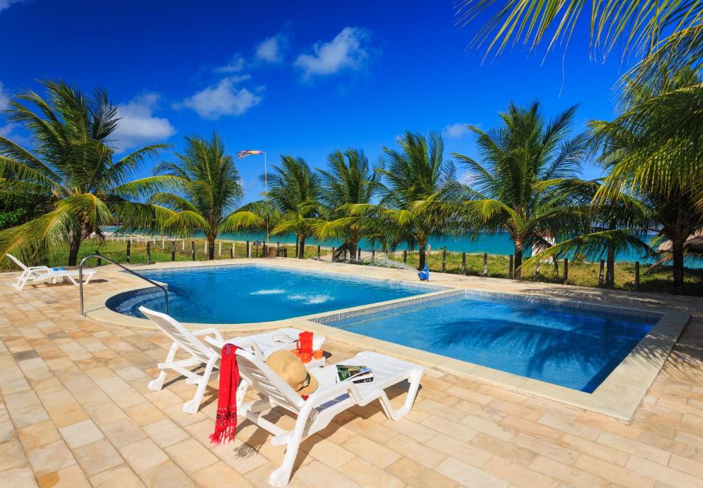 a swimming pool with two chairs and a table at Chales Maragogi in Maragogi