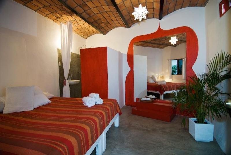 a bedroom with a large bed and a bathroom at Petit Hotel Hafa in Sayulita