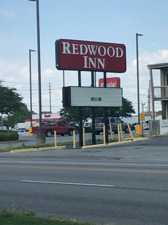 una señal para una posada de madera roja en un estacionamiento en Redwood Inn, en Gadsden