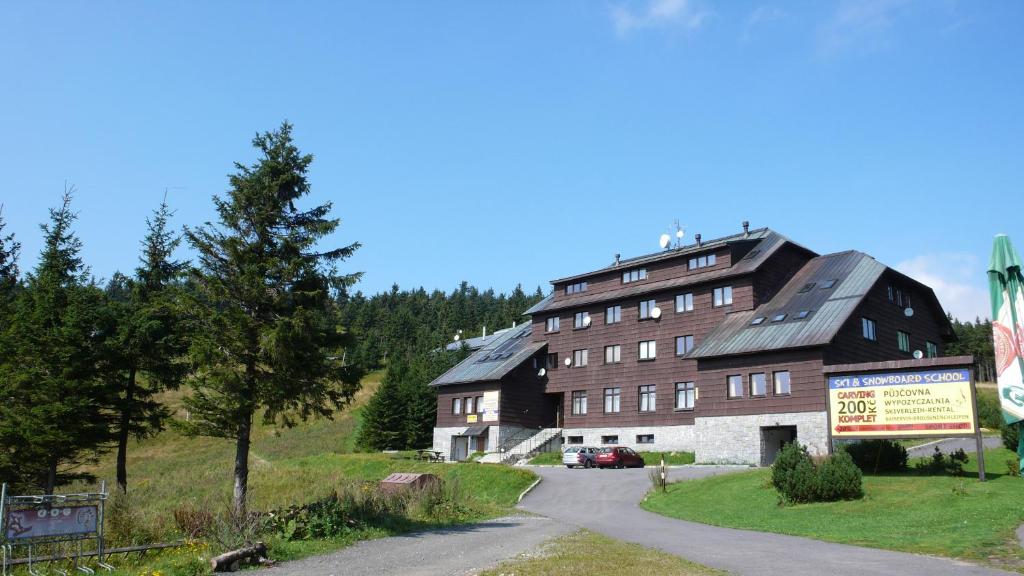 a large building on a hill next to a road at Apartmány Červenohorské sedlo in Kouty