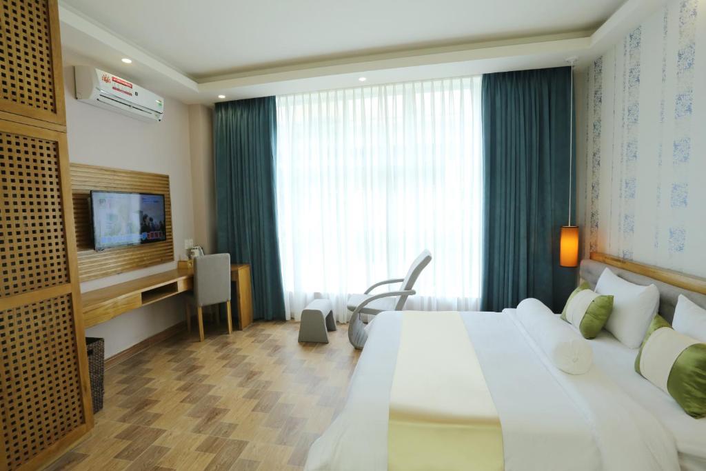 Thuy Sakura Hotel & Serviced Apartment في مدينة هوشي منه: غرفه فندقيه سرير كبير وتلفزيون