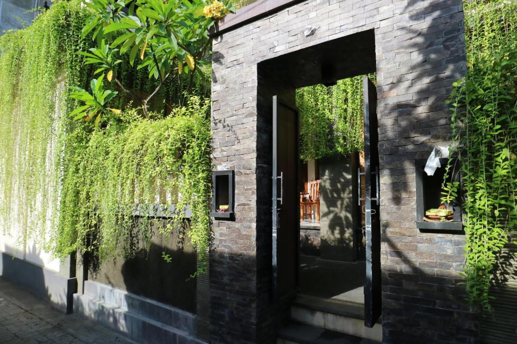 a brick building with an open door and ivy at Pondok 3 Mertha in Kuta