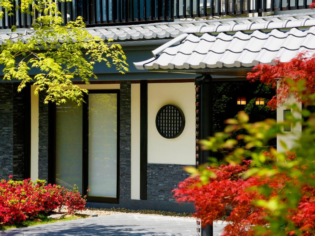 budynek z czerwonymi kwiatami przed nim w obiekcie Ryokan KANADE w mieście Kioto