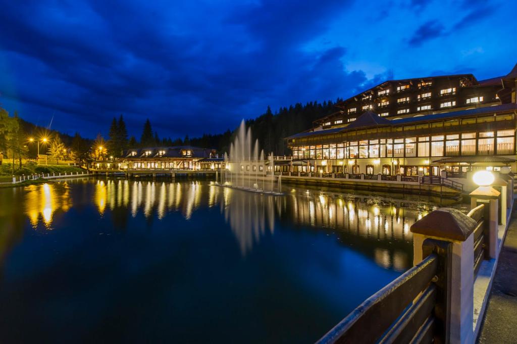 un edificio con una fuente en el agua por la noche en Aurelius Imparatul Romanilor en Poiana Brasov