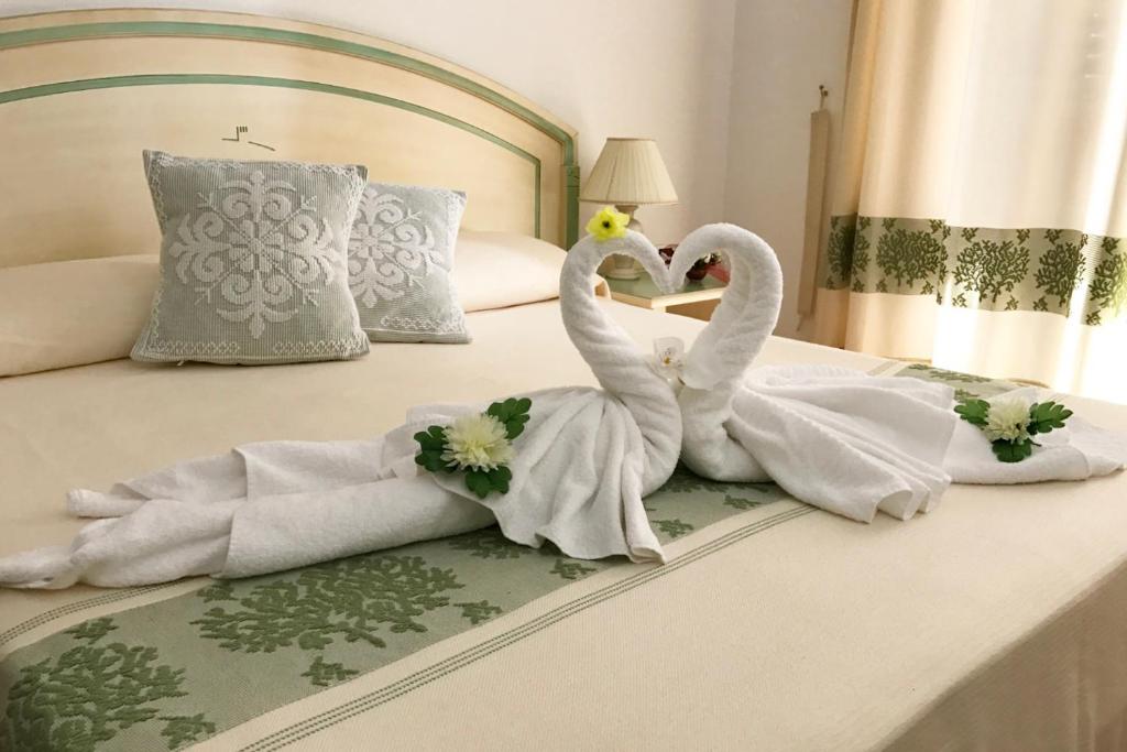 two swans dressed in towels sitting on a bed at Guest House Villabianca in La Maddalena