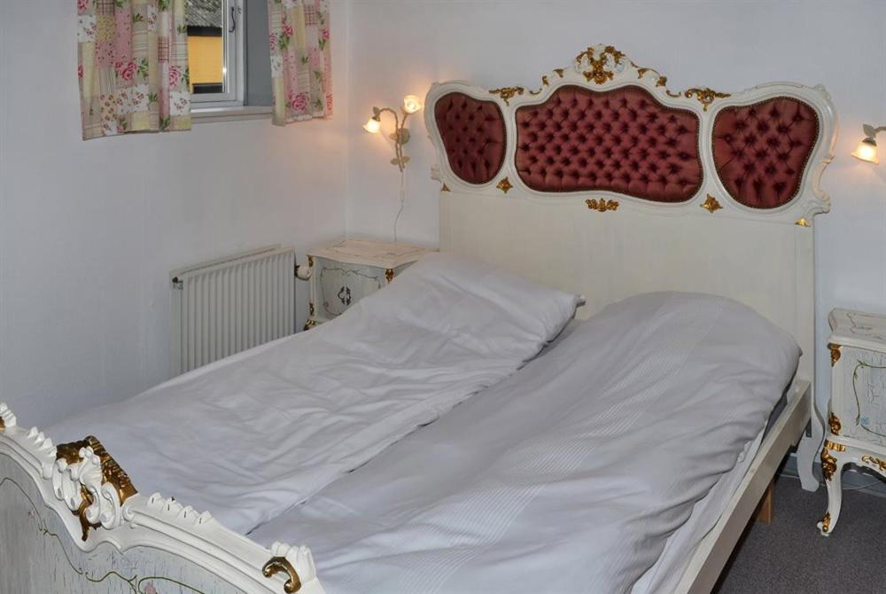 a white bed with a red headboard in a bedroom at Motel Lido in Bredebro