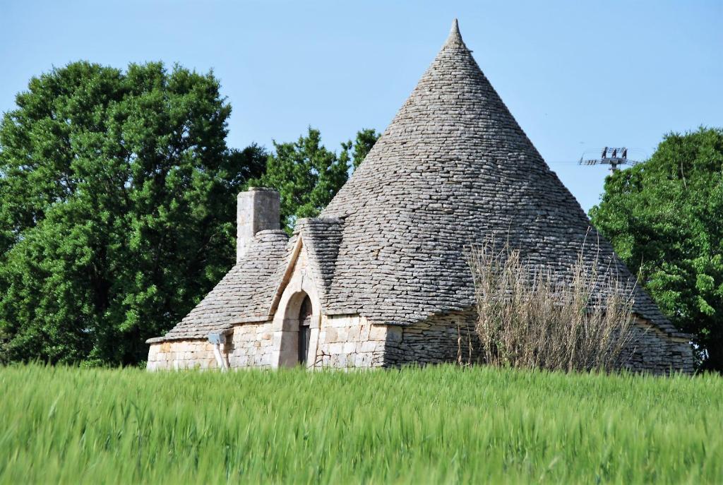 an old stone cottage in a field of grass at Iannet & Co. in Locorotondo