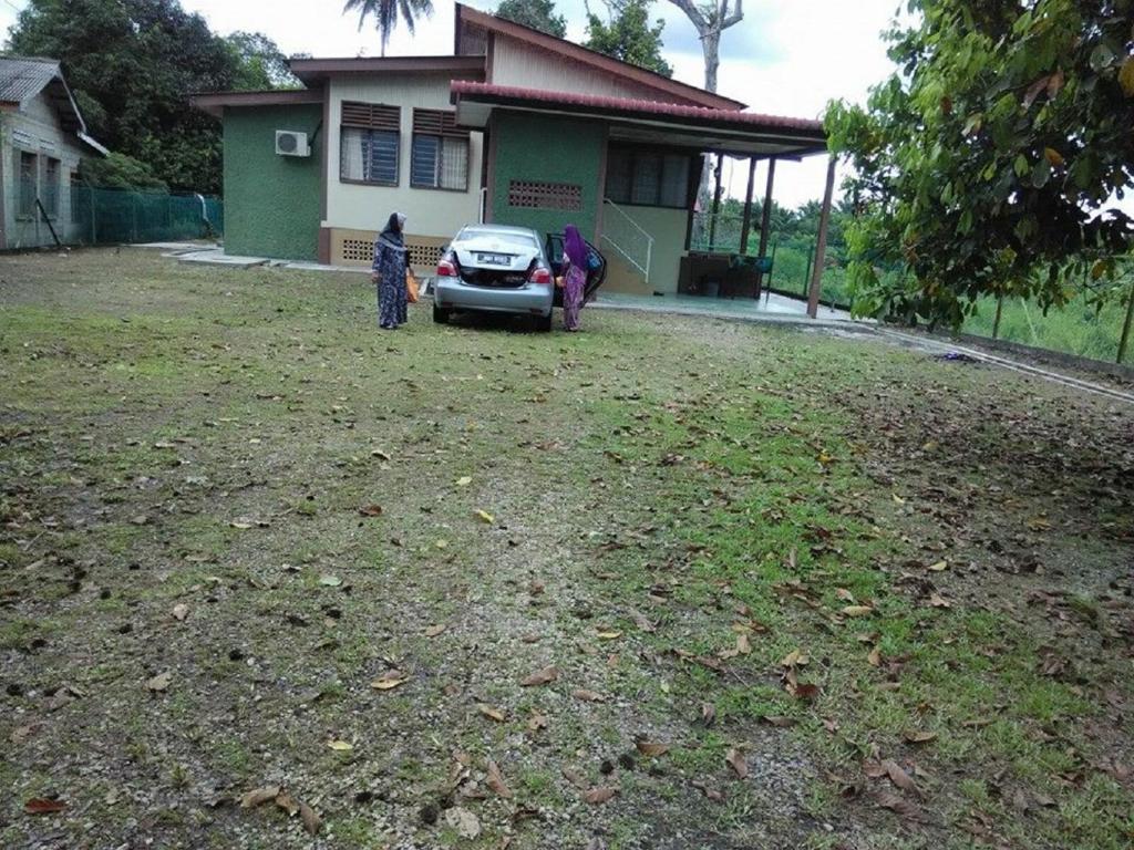 dos personas de pie en frente de una casa con un coche en Villasayang Homestay en Mersing