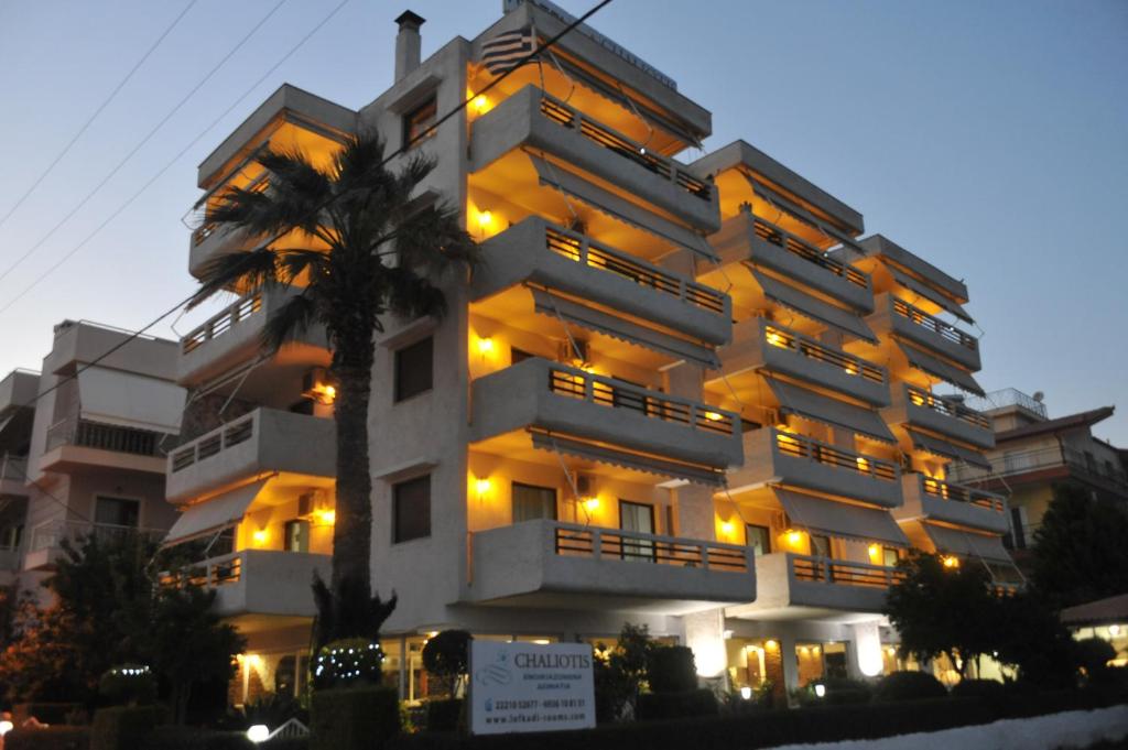 a large white building with a palm tree in front of it at Chaliotis Apartments in Lefkandi Chalkidas