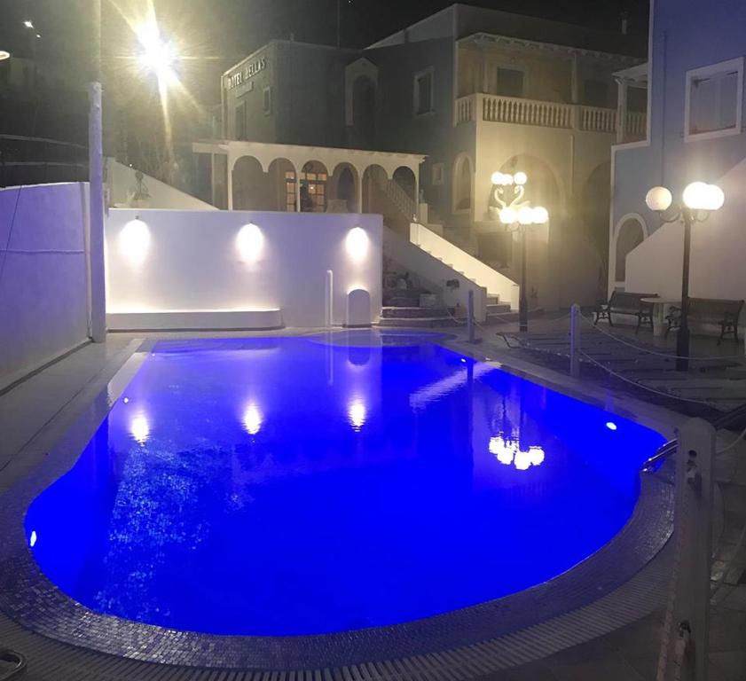 a large blue swimming pool at night with lights at Hotel Hellas in Fira