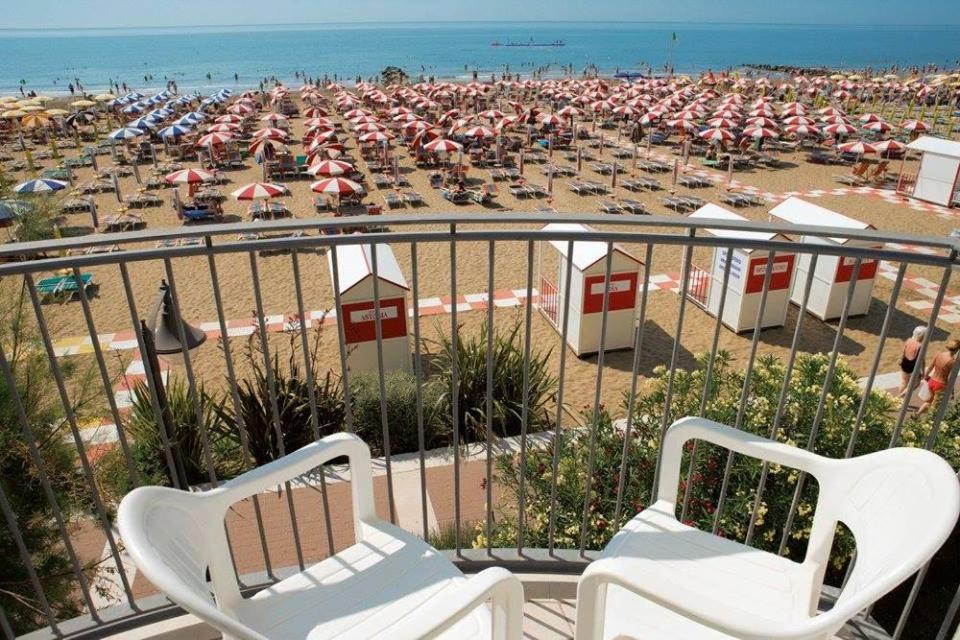 een uitzicht op een strand met stoelen en parasols bij Hotel Vienna in Caorle