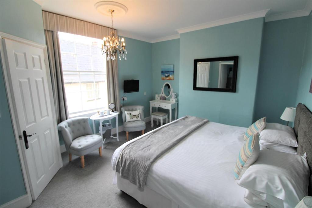 a bedroom with blue walls and a bed and a desk at The Lorna Doone Hotel in Porlock