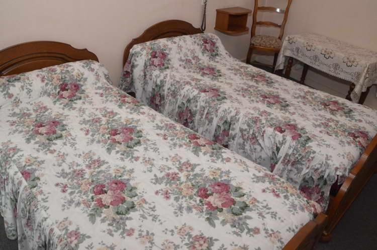 two beds in a room with flowers on them at Hotel du Commerce in Pont-de-Vaux