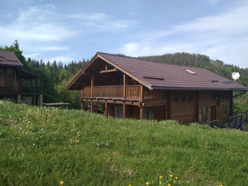 una cabaña de madera en una colina en un campo en Cottage Kurshevel, en Slavske