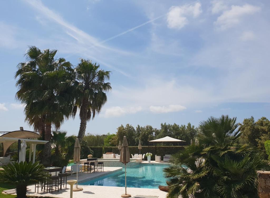 a swimming pool with palm trees and umbrellas at Su Soi in Càbras