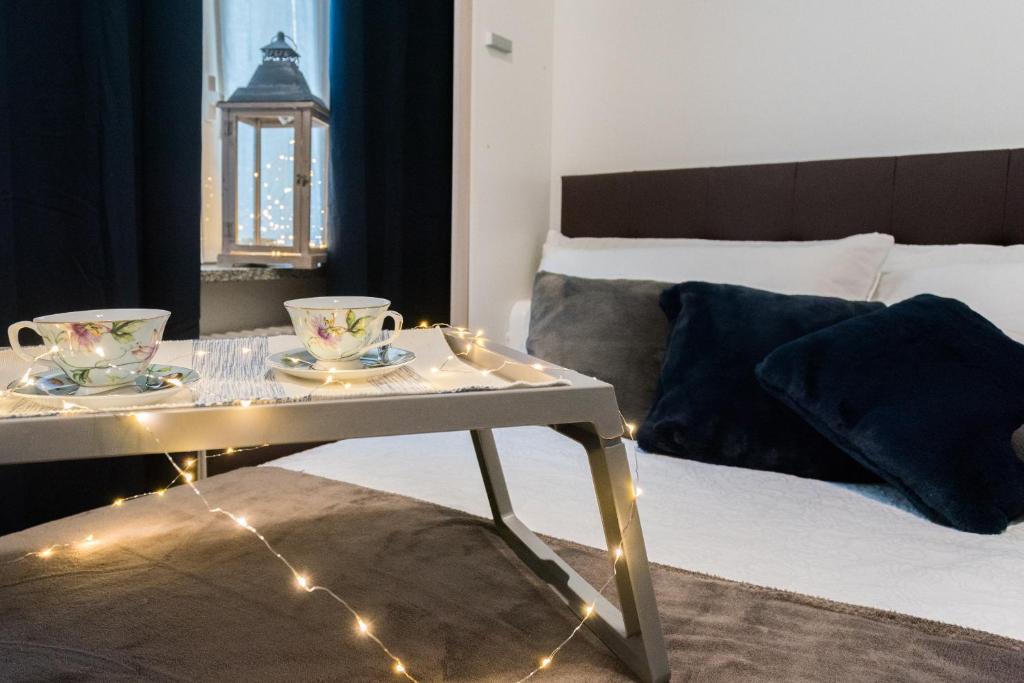 una camera da letto con tavolo, tazze da tè e luci di Love & Smile Apartment by Rent All Como a Como