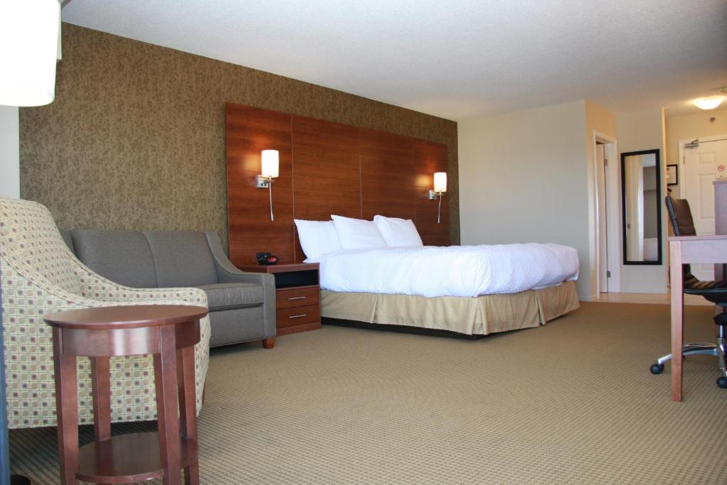a hotel room with a bed and a chair at Budget Host Inn & Suites in Saint Ignace