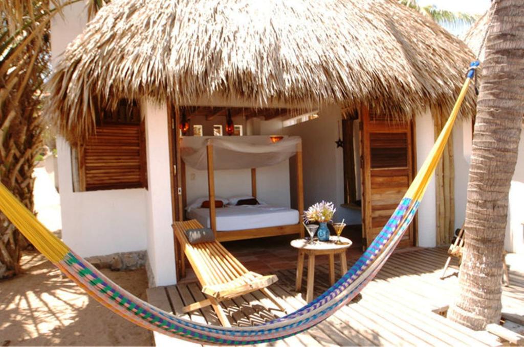 a hammock in front of a room with a bed at Un Sueño Cabañas del Pacífico in San Agustinillo