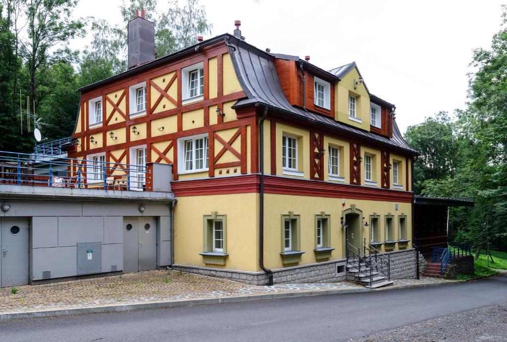 een groot oranje en geel huis met een garage bij Spa Resort Libverda - Hotel Lesní Zátiší in Lázně Libverda