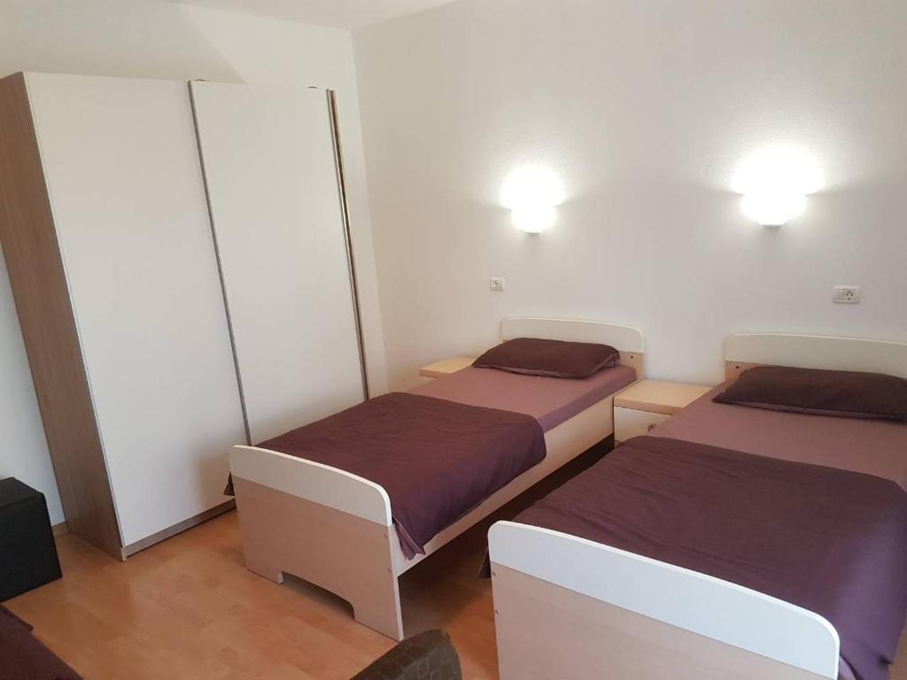 two beds in a small room with two lamps at KEI apartment in Portorož