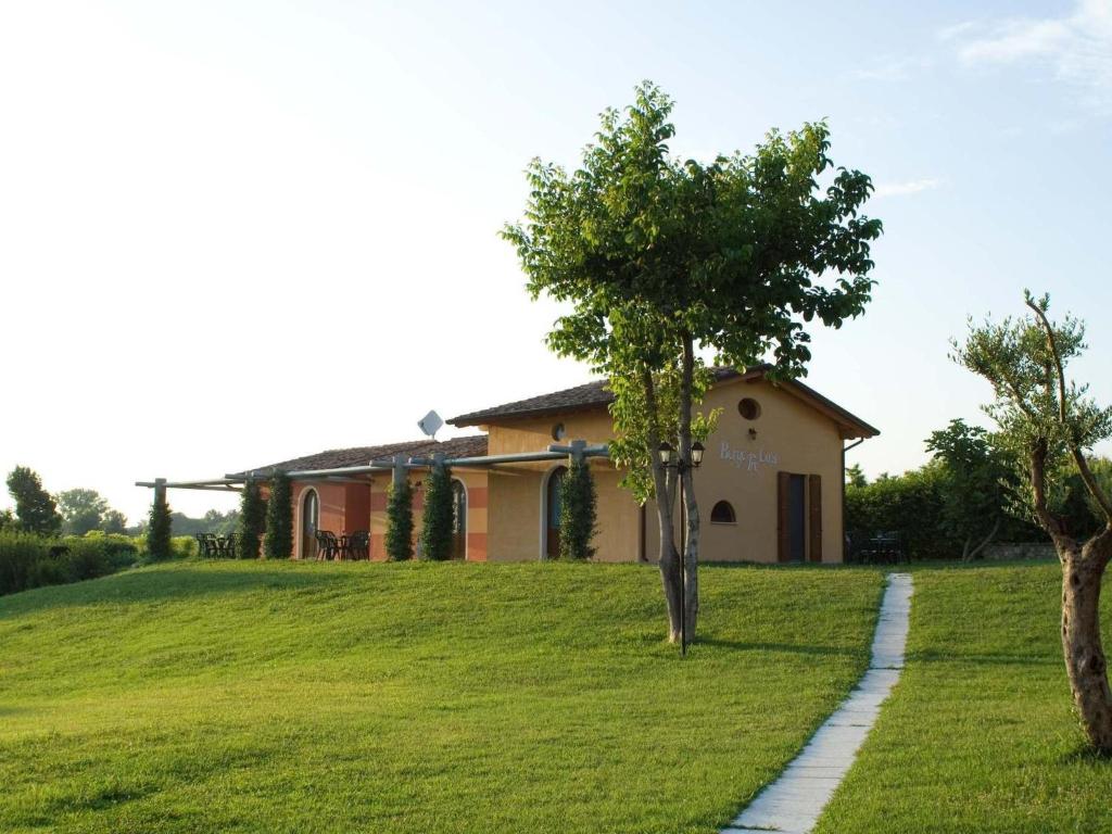 uma casa numa colina com uma árvore em primeiro plano em B&B Borgo Tre Case em Cavriana