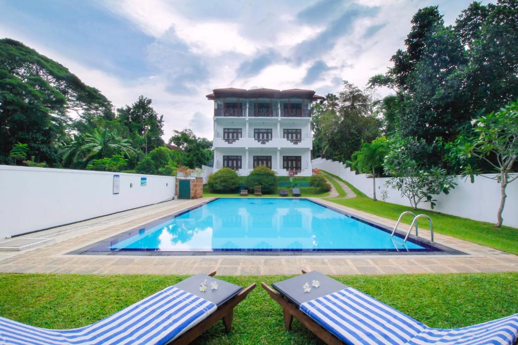 a house with a swimming pool and two lawn chairs at Rockery Villa Ayurveda in Bentota