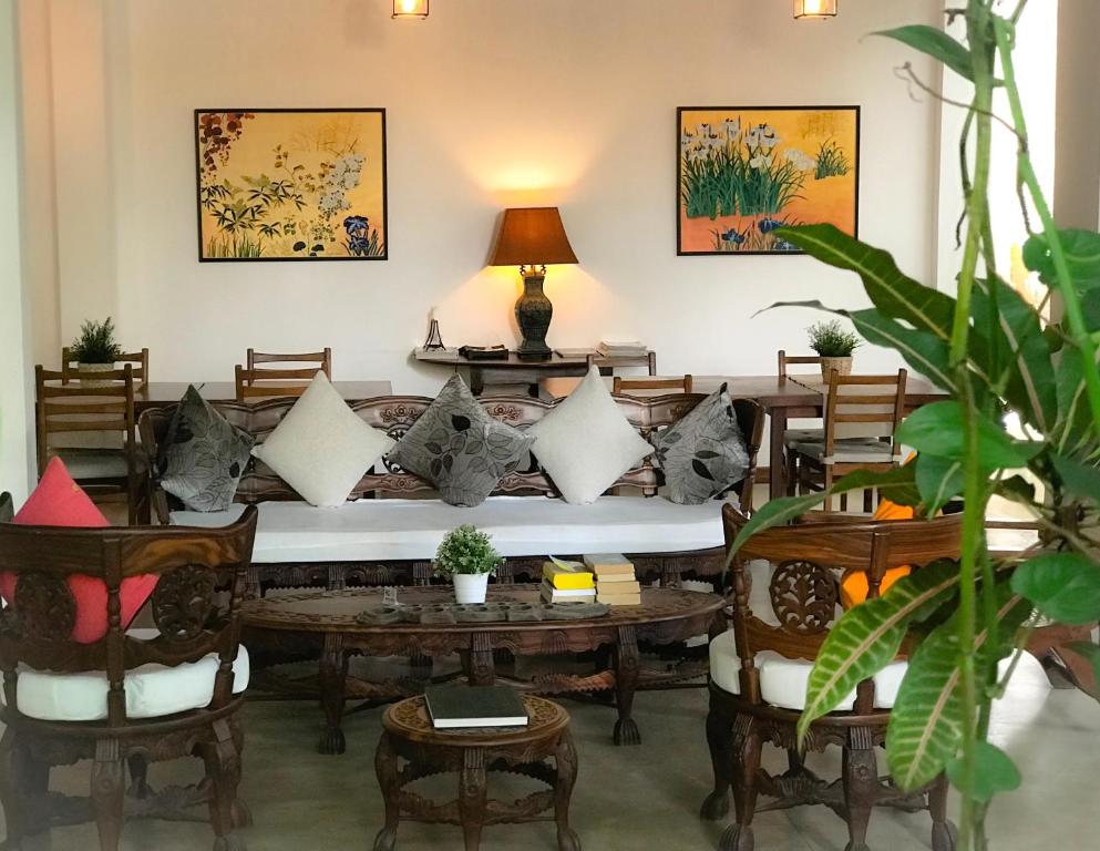 uma sala de estar com um sofá, mesas e cadeiras em Sayura House em Colombo