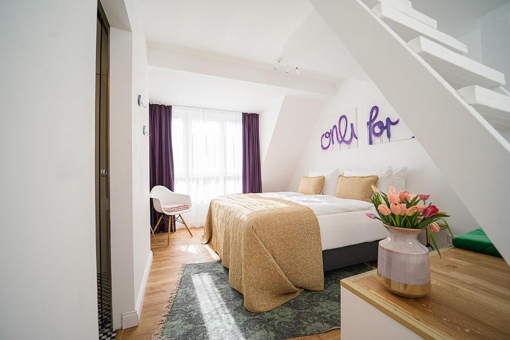 a white bedroom with a bed and a vase of flowers at Victoria Hotel in Düsseldorf