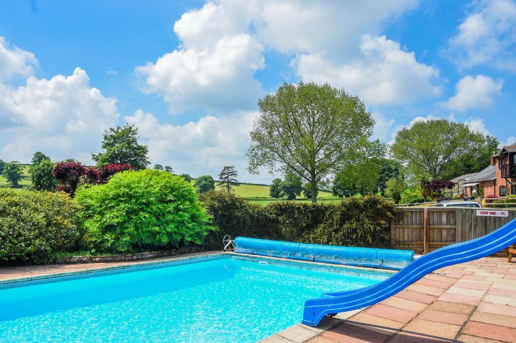 a swimming pool with a slide in a yard at Honeysuckle Cottage in Hele