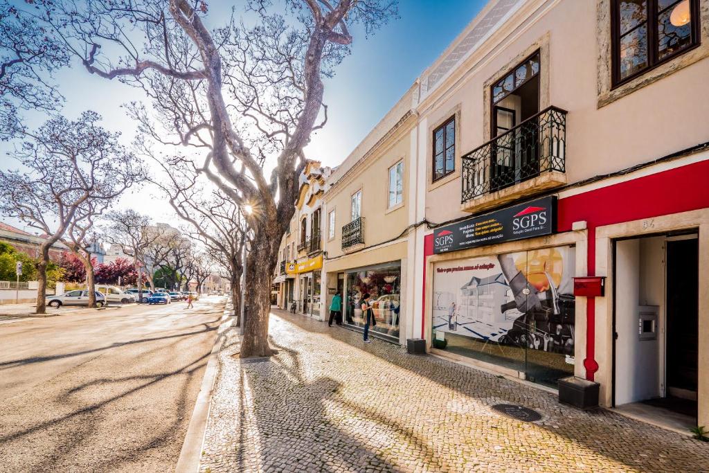 a street with buildings and a tree on the sidewalk at Maria's 5th Avenue in Setúbal