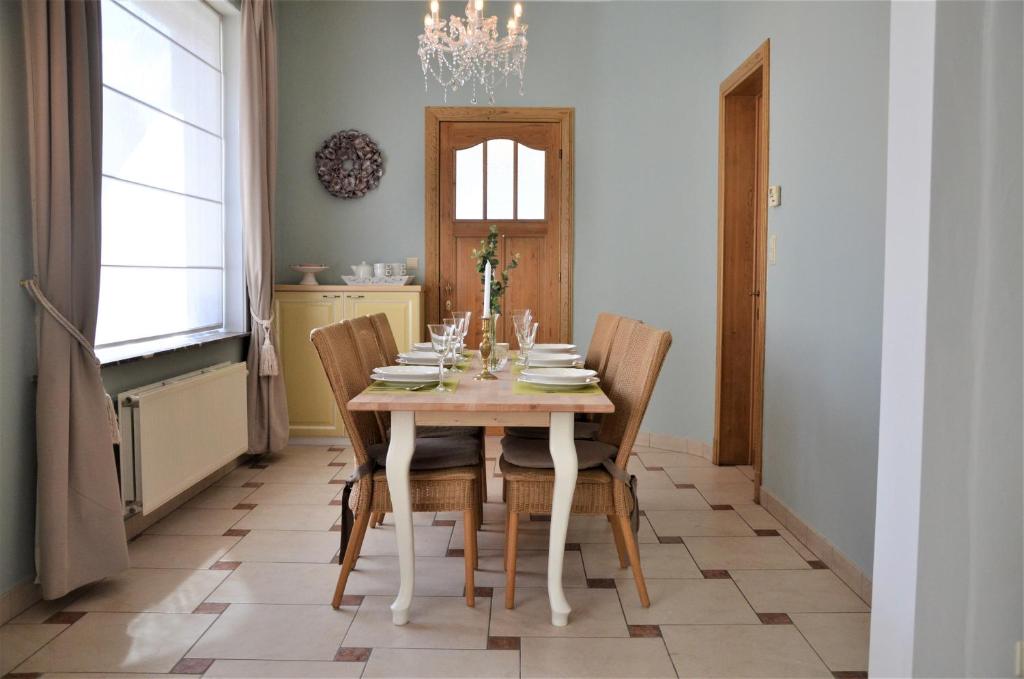 una sala da pranzo con tavolo, sedie e lampadario pendente di Ciepers Lodge a Ypres