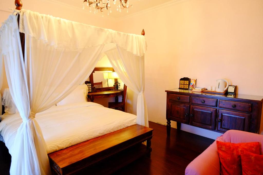 花蓮市的住宿－眠月樓民宿 ，一间卧室配有一张天蓬床和木制梳妆台。