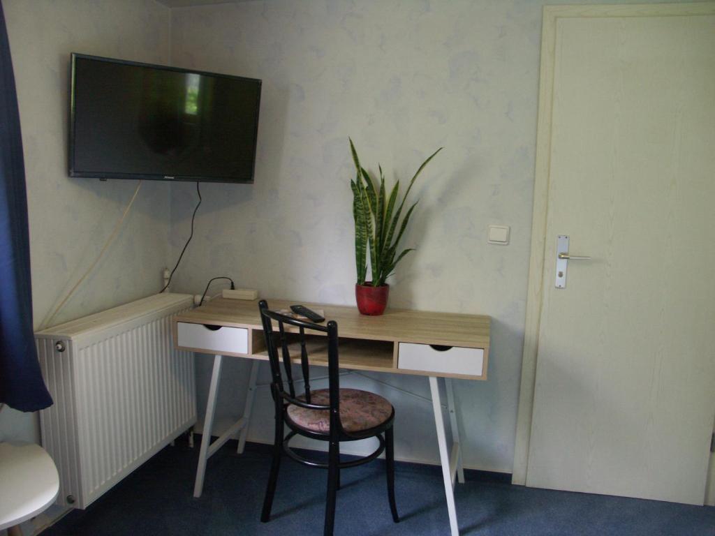 a desk with a chair and a television on a wall at Waldpension zum Felsenkeller in Lichtenfels-Sachsenberg