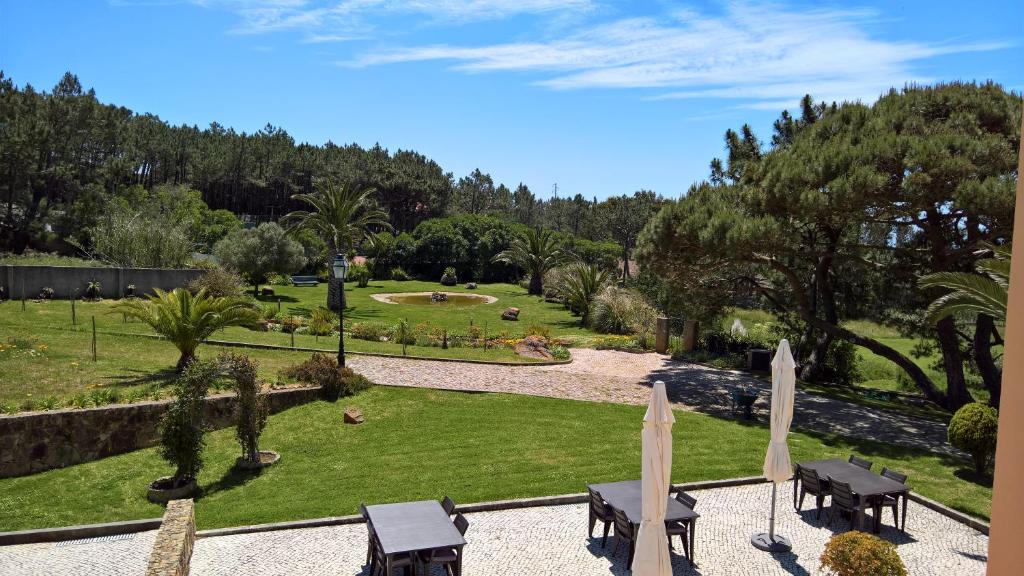 a park with tables and chairs and a park with trees at Quinta do Cabo Guesthouse in Sintra