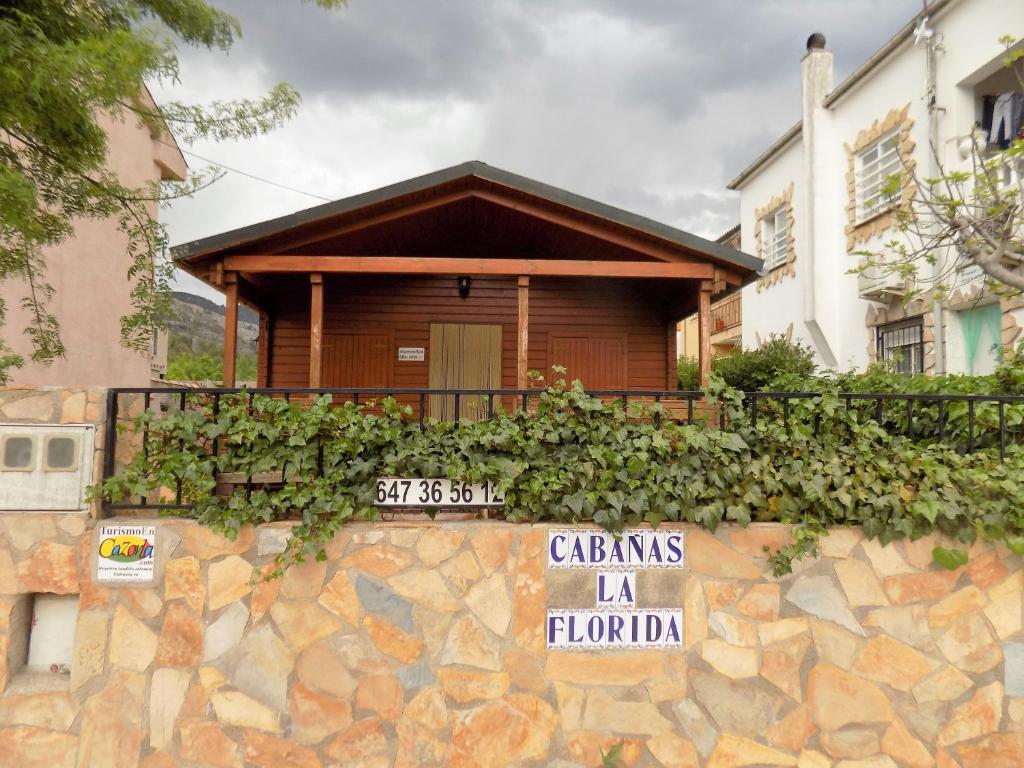 une maison avec un panneau sur un mur en pierre dans l'établissement CABAÑAS DE MADERA LA FLORIDA, à Arroyo Frío